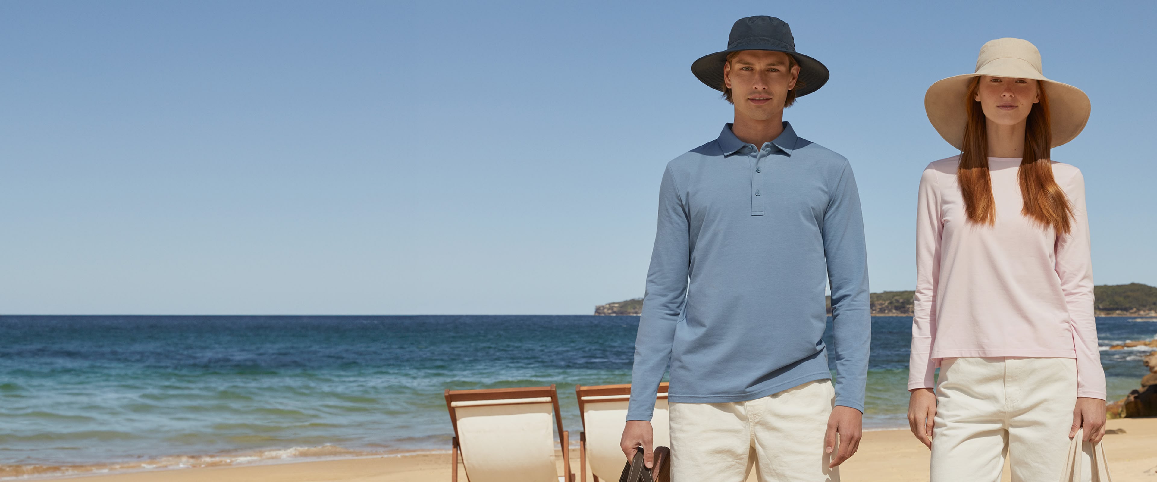 A man and a woman in upf 50+ solbari clothing with the beach and sea behind them.