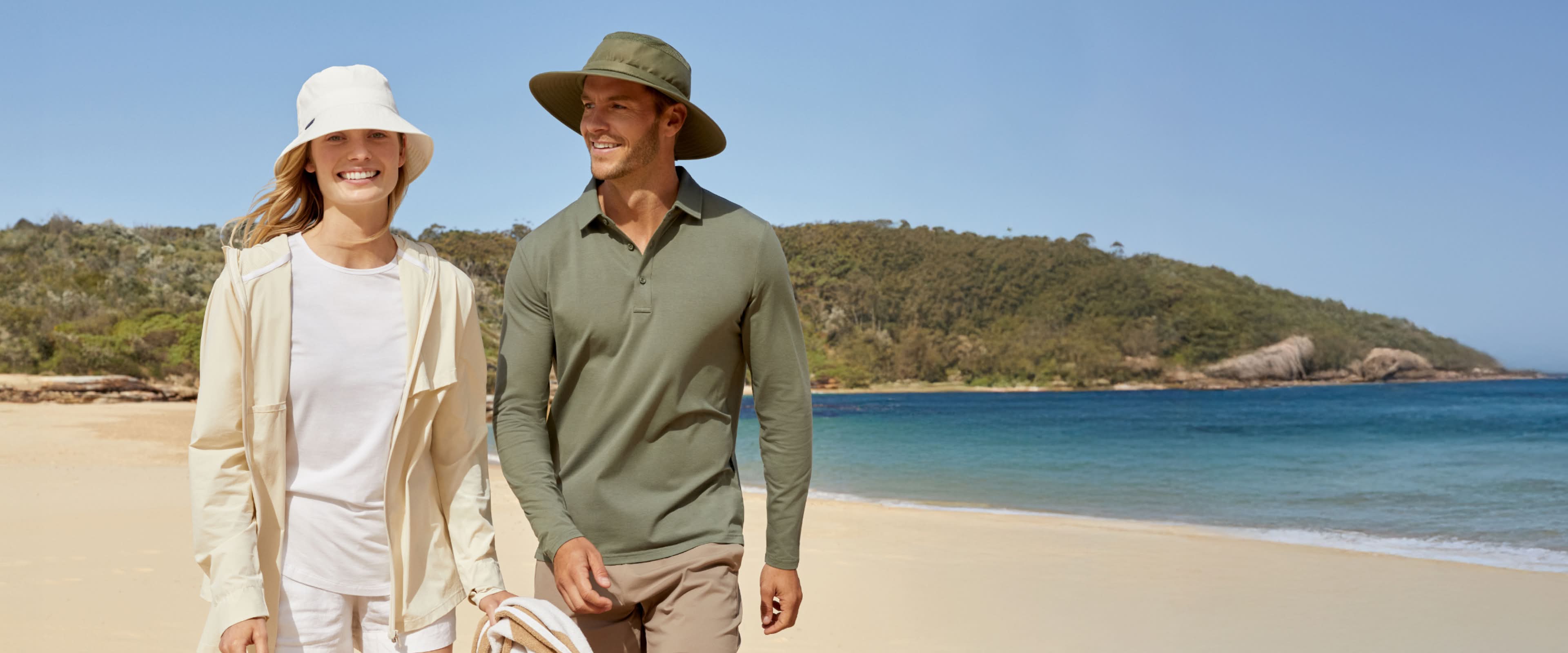 A woman and a man walking along a beach on a sunny day.