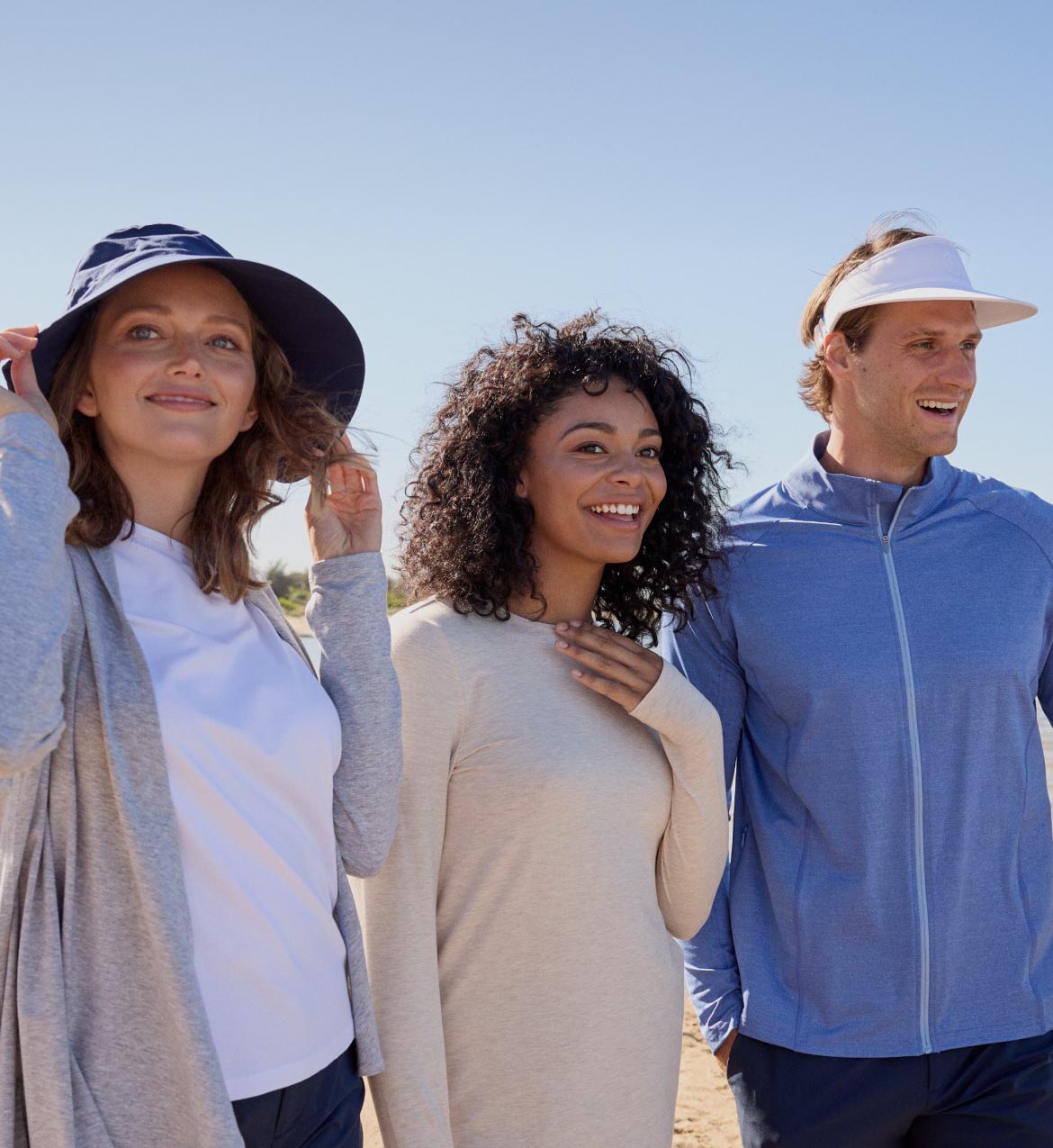 Three people smiling with a blue sky in the background.