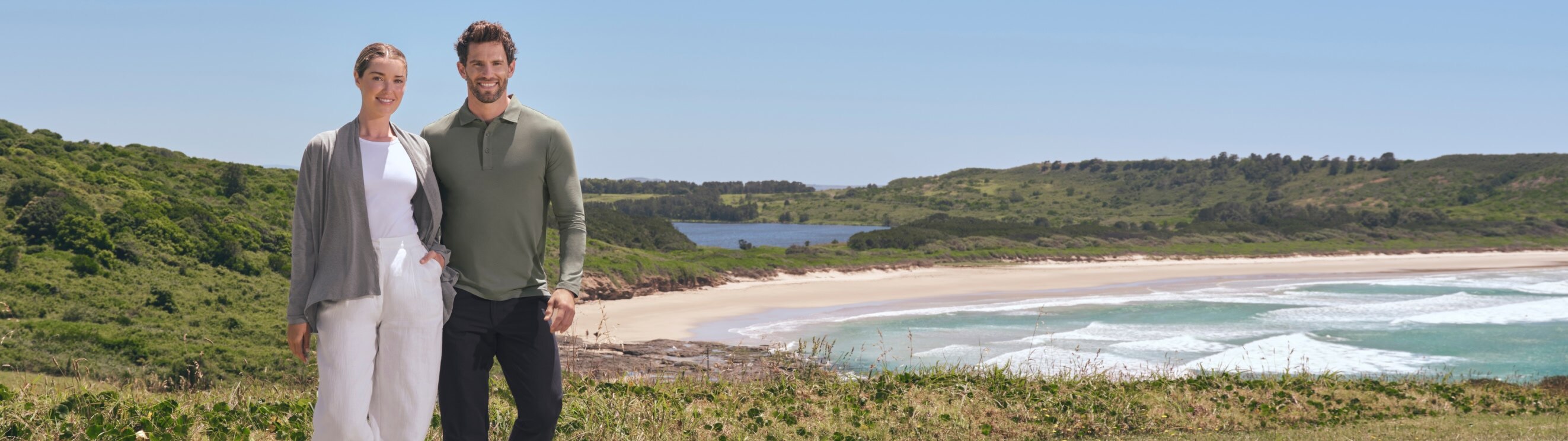 An image of a woman and a mean standing on a green hillside wearing Solbari sun protective UPF 50+ clothing.