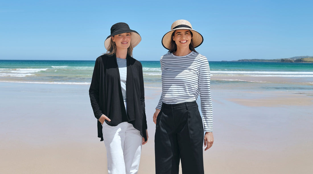Two women on a beach wearing Solbari sun hats and sun protective clothing