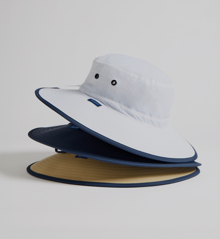 A pile of three sun hats in different colours on a light grey background.