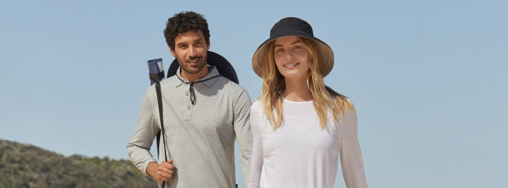 A man and woman outside with sun hats on with a blue sky in the background.