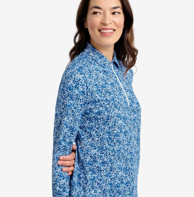 A woman in a blue printed top looking over her shoulder.