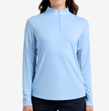 A person wearing a blue top with high neck and full length sleeves, against a white background.