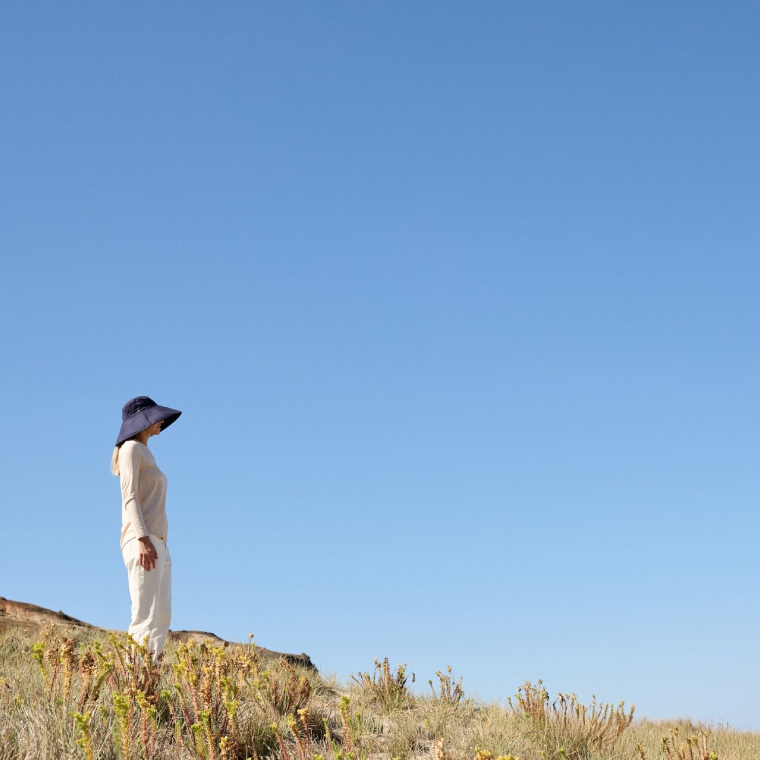 a woman walking wearing a Solbari sunhat and clothing.