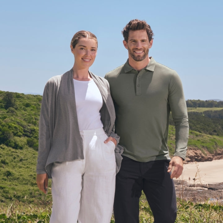 An image of a woman and a mean standing on a green hillside wearing Solbari sun protective UPF 50+ clothing.
