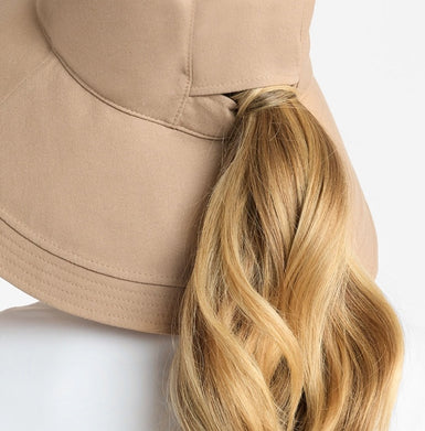 A beige hat showing a ponytail hole.
