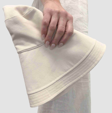 Someone holding a white folded packable sun hat.