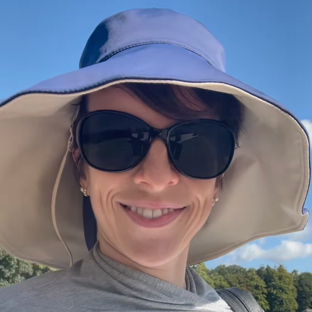 A woman wearing a blue and beige wide brimmed Solbari sun hat.