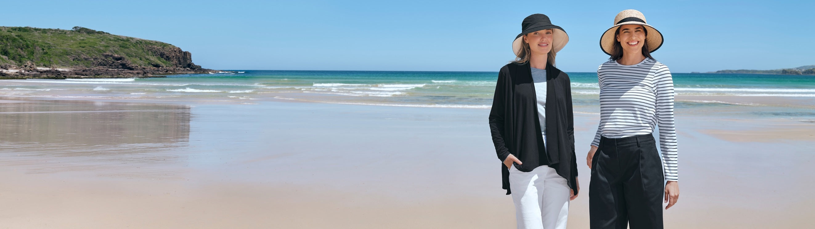 An image of two women on a beach wearing Solbari sun protective clothing and UPF 50+sun hats, with the sea behind them.
