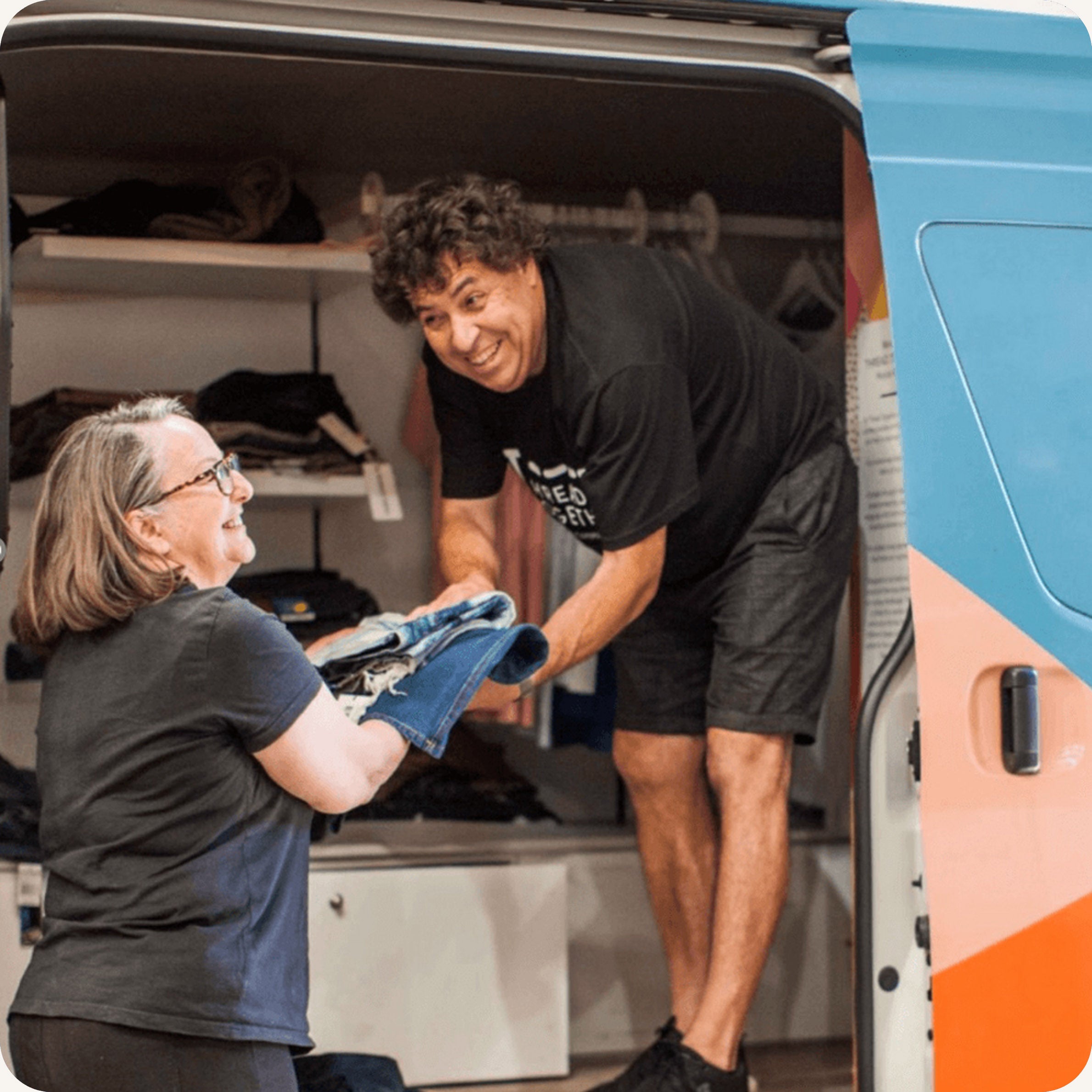 A man handing some clothing to a woman from a van